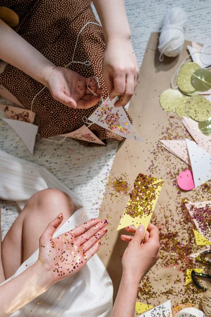 Hands crafting with glitter and paper for festive decorations, showcasing creativity and DIY skills.